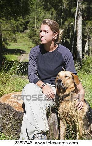 Stock Photograph - A Girl Sits Relaxing Outside On A Warm Summers Day With Her Dog At Blue Duck Lodge, In Whanganui National Park; Whakahoro, New Zealand. Fotosearch