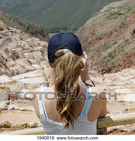 Stock Photo - A Girl Takes A Picture Of The Salt Mines In Sacred Valley; Maras Peru. Fotosearch