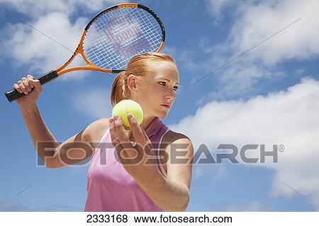 Stock Photo - A girl with a tennis ball and racquet; Oahu, Hawaii, United States of America. Fotosearch