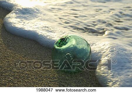 A Glass Fishing Float Rolls On The Sandy Shoreline With Ripples Of Water And Seafoam View Large Photo Image Stock Photo - A Glass Fishing Float Rolls On The Sandy Shoreline With Ripples Of Water And Seafoam. Fotosearch
