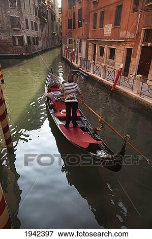A Gondolier Gives A Ride To Passengers In His Gondola; Venice Italy View Large Photo Image Stock Photo - A Gondolier Gives A Ride To Passengers In His Gondola; Venice Italy. Fotosearch