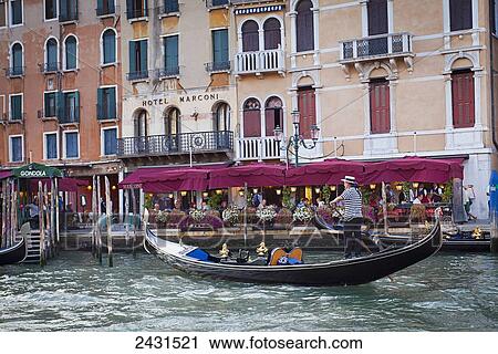 Stock Image - A gondolier in a gondola outside Hotel Marconi; Venice, Italy. Fotosearch