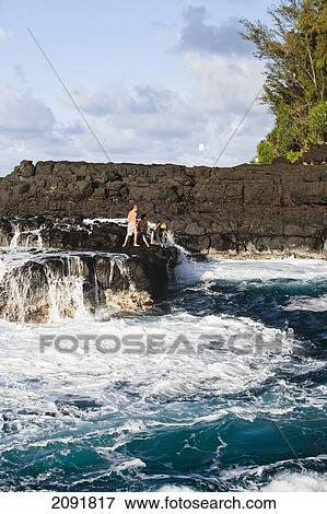 Stock Photo - A Group Looks Out To Sea At The Queen's Bath; Princeville, Kauai, Hawaii, Usa. Fotosearch