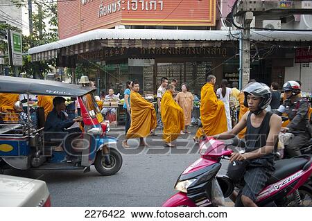 Stock Image - A group of Buddhist monks on their morning alms round; Bangkok, Thailand. Fotosearch