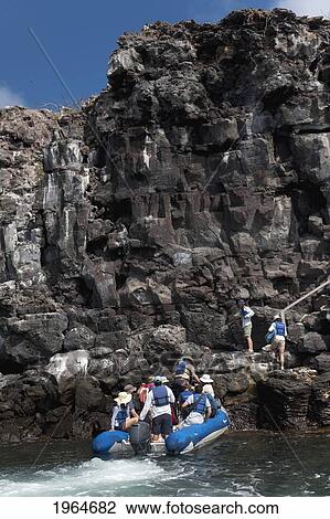 Stock Image - A Group Of People Disembark An Inflatable Raft Onto Rugged Terrain; Galapagos Equador. Fotosearch