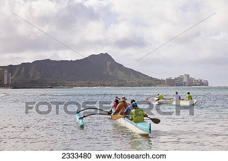 Stock Image - A Group Of People In An Outrigger Canoe; Oahu, Hawaii, United States Of America. Fotosearch