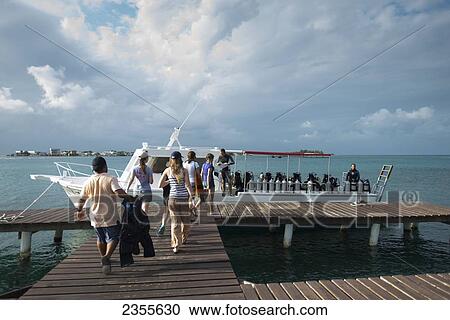 Stock Image - A Group Of Tourists Walk Out To A Scuba Diving Boat; Utila Island, Honduras. Fotosearch