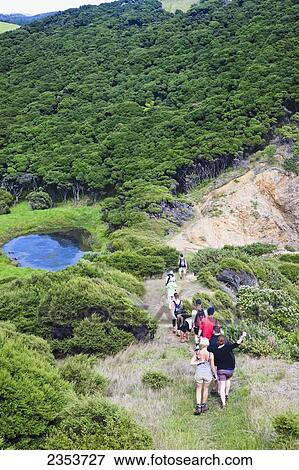 Stock Photo - A Group Of Tourists Walking In A Row Down A Trail On Urupukapuka Island; New Zealand. Fotosearch