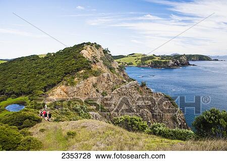 Stock Photo - A Group Of Tourists Walking In A Row Down A Trail On Urupukapuka Island; New Zealand. Fotosearch