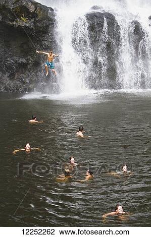 Stock Image - A group of travelers gather to play in the Tad Yuang Waterfall on the Bolaven Plateau; Laos. Fotosearch