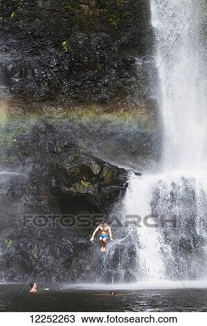 Stock Image - A group of travelers gather to play in the Tad Yuang Waterfall on the Bolaven Plateau; Laos. Fotosearch