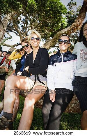 Stock Photo - A Group Of Young Adults Pose By A Tree On An Island In The Bay Of Islands; Urupukapuka Island, New Zealand. Fotosearch