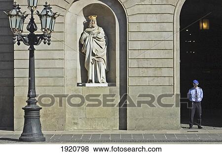 Stock Photo - A Guard Is Being Watched Over By A Statue At The Adjustment City Hall; Barri Gotic, Barcelona. Catalonia, Spain. Fotosearch