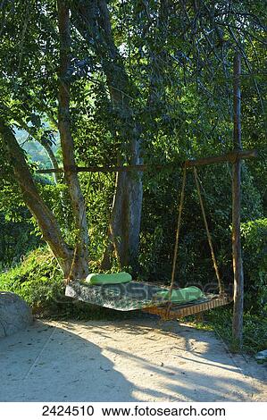 Stock Image - A hammock hanging beside trees; Ulpotha, Embogama, Sri Lanka. Fotosearch