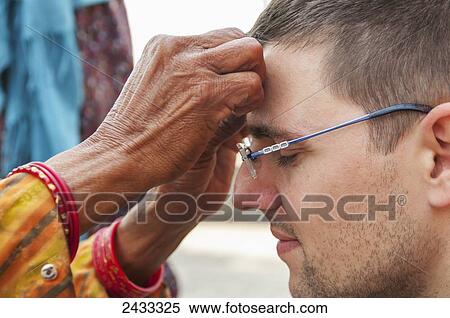 Stock Photography - A hindu woman putting a third eye on a tourist in Swayambhu temple; Kathmandu, Nepal. Fotosearch