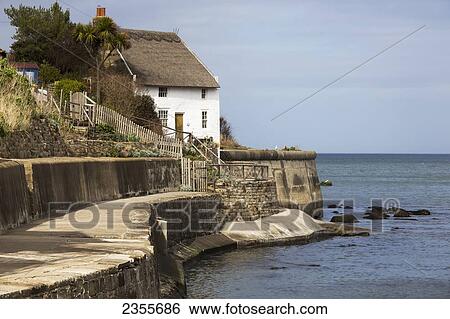 Stock Photograph - A House And Paved Path Along The Water's Edge; Runswick Bay, Yorkshire, England. Fotosearch