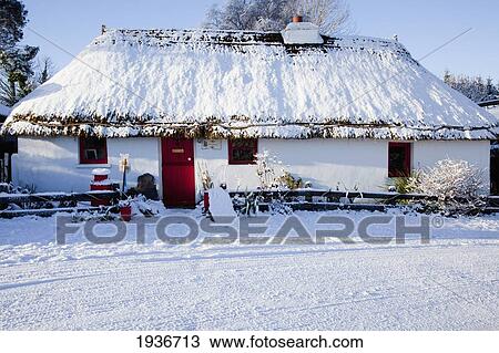 Stock Image - A House With A Red Door Covered In Snow; Currabinny County Cork Ireland. Fotosearch