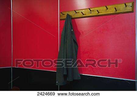 Stock Photo - A jacket hangs on a hook mounted on a bright red wall; London, England. Fotosearch