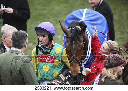 Stock Image - A jockey with the champion trainer after winning the Champion Chase horse race; Cheltenham, Gloucestershire, England. Fotosearch