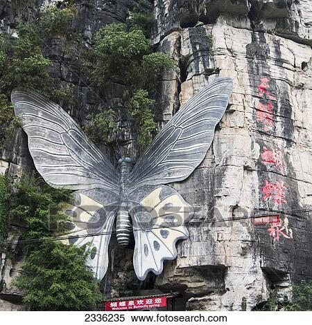 Stock Photography - A Large Butterfly Mounted On A Mountainside Above A Sign; Guilin, Guangxi, China. Fotosearch