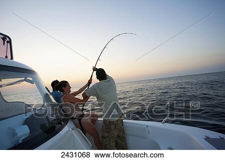 Stock Photo - A large catch bends the fishing rod while fishing at sunset; Vamizi Island, Mozambique. Fotosearch