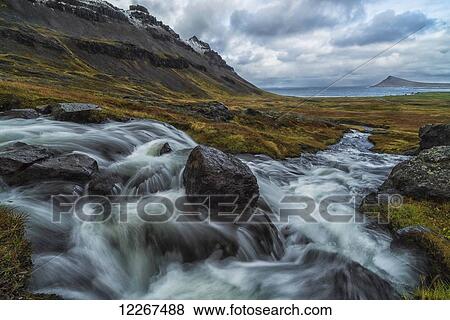 Stock Photo - A large stream runs down a hillside creating a waterfall along the Strandir Coast in the West Fjords of Iceland; Iceland. Fotosearch