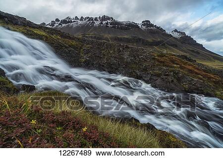 Stock Photo - A large stream runs down a hillside creating a waterfall along the Strandir Coast in the West Fjords of Iceland; Iceland. Fotosearch