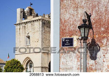 Stock Image - A Light Mounted On The Side Of A Building And A Bell Tower; Faro Algarve Portugal. Fotosearch