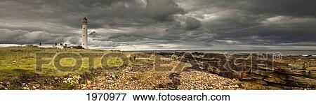 Stock Photo - A Lighthouse And Piles Of Logs On The Shore; Lothian Scotland. Fotosearch