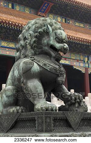 Stock Photo - A Lion Statue In Front Of A Building With Colourful Ornate Facade At Forbidden City; Beijing, China. Fotosearch