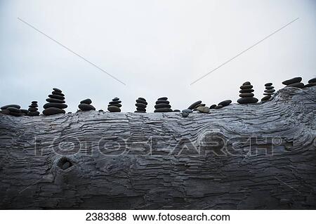 Stock Photo - A log with piles of rocks stacked by people on Ruby Beach; Washington, United States of America. Fotosearch