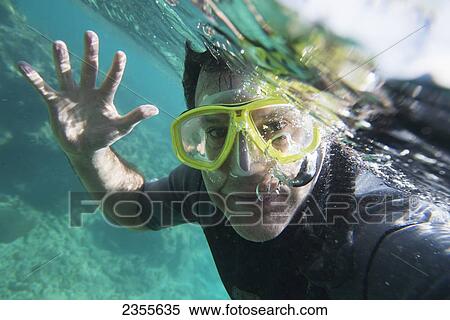 Stock Photography - A Male Scuba Diver Waves Hello Underwater; Utila Island, Honduras. Fotosearch