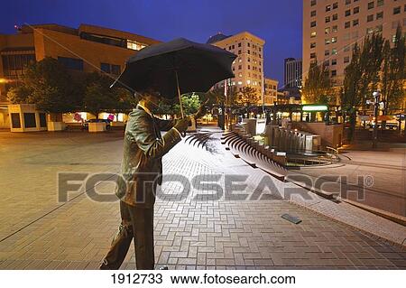 Stock Image - A Male Statue With An Umbrella In The Early Morning In Pioneer Courthouse Square; Portland, Oregon, United States Of America. Fotosearch