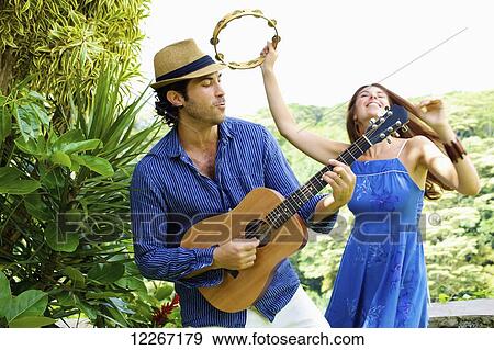 Stock Photo - A man and woman playing music on guitar and tambourine; Wailua, Kauai, Hawaii, United States of America. Fotosearch