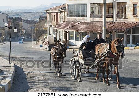 Stock Image - A Man And Woman Ride In A Horse Drawn Carriage With Another Horse Tied To The Back Of The Carriage; Ortahisar Nevsehir Turkey. Fotosearch