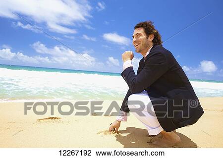 Stock Image - A man barefoot on the beach; Kealia, Kauai, Hawaii, United States of America. Fotosearch