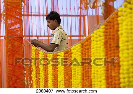 Stock Photo - A Man Hanging Yellow And Orange Decorations; Ludhiana, Punjab, India. Fotosearch