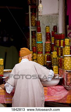 Stock Image - A Man Lays Out Preserved Lemons And Olives In The Olive Souq; Marrakech, Morocco. Fotosearch