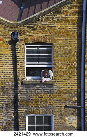 A man leans out the window of a brick residential building looking below; London, England View Large Photo Image Stock Photo - A man leans out the window of a brick residential building looking below; London, England. Fotosearch