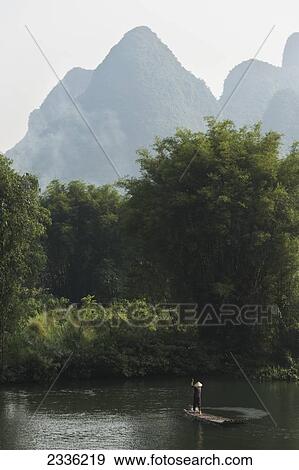 A Man Paddles In The Yulong River; Yangshuo, Guangxi, China View Large Photo Image Stock Photo - A Man Paddles In The Yulong River; Yangshuo, Guangxi, China. Fotosearch