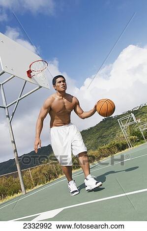 Stock Image - A man playing basketball; Oahu, Hawaii, United States of America. Fotosearch