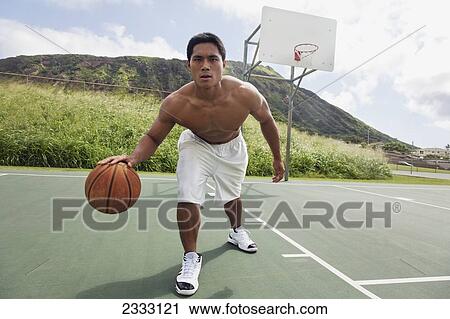 Stock Image - A man playing basketball; Oahu, Hawaii, United States of America. Fotosearch
