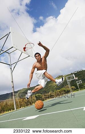 Stock Image - A man playing basketball; Oahu, Hawaii, United States of America. Fotosearch