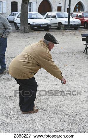 A man playing boule on a winter day in the main square; Castelnau-Montratier, Lot region, Midi-Pyrenees, France View Large Photo Image Stock Photo - A man playing boule on a winter day in the main square; Castelnau-Montratier, Lot region, Midi-Pyrenees, France. Fotosearch