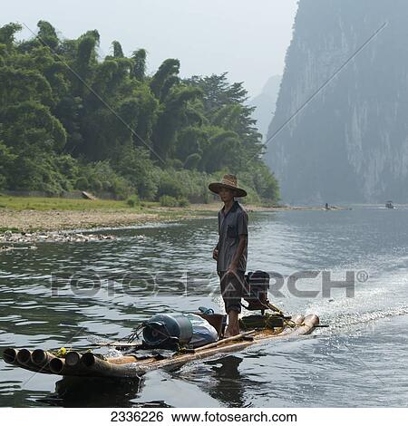 Stock Photograph - A Man Riding A Motorized Raft Down The River Li; Guilin, Guangxi, China. Fotosearch