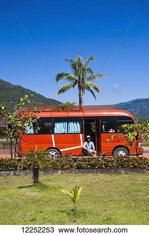 Stock Image - A man sits and waits in a tour bus after a temple tour; What Phu, Laos. Fotosearch