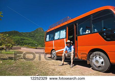 A man sits and waits in a tour bus after a temple tour; Wat Phu, Loas View Large Photo Image Stock Photo - A man sits and waits in a tour bus after a temple tour; Wat Phu, Loas. Fotosearch