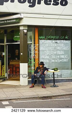 Stock Photo - A man sits at a table outside a cafe, Portobello Road Market; London, England. Fotosearch