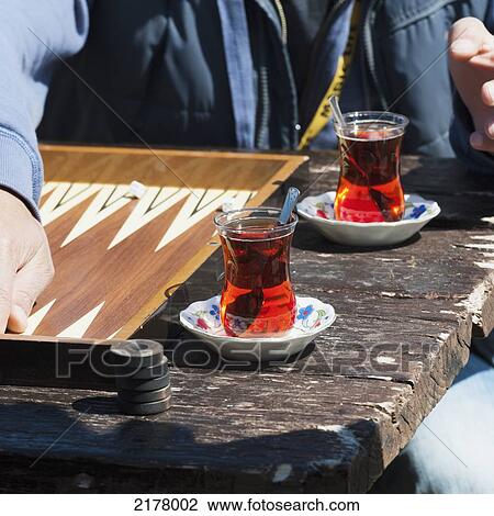 Stock Image - A Man Sits At A Table With Two Beverages And The Game Of Backgammon; Avanos Nevsehir Turkey. Fotosearch