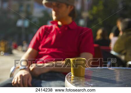 A man sits at an outdoor cafe with a coffee cup on the table; Barcelona, Spain View Large Photo Image Stock Photo - A man sits at an outdoor cafe with a coffee cup on the table; Barcelona, Spain. Fotosearch